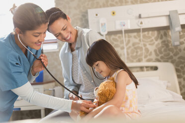Krankenschwester mit Stethoskop auf Teddybär von Mädchen Patienten im Krankenhaus Zimmer - HOXF01743