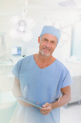 Porträt eines männlichen Chirurgen, der ein digitales Tablet im Operationssaal benutzt - HOXF01751