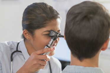 Female doctor using otoscope in ear of patient - HOXF01766