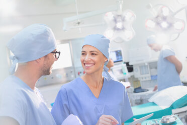 Lächelnde Chirurgen im Gespräch im Operationssaal - HOXF01767