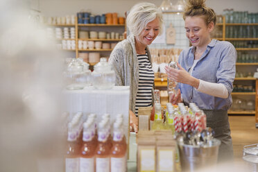 Shop owner showing products to female shopper in shop - HOXF01781