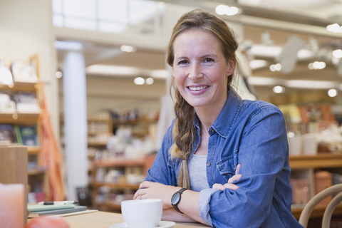 Porträt einer lächelnden Frau, die in einem Cafe Kaffee trinkt, lizenzfreies Stockfoto
