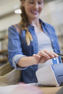 Weibliche Kundin benutzt ein Kreditkartenlesegerät in einem Geschäft - HOXF01802