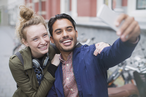 Smiling young couple taking selfie with camera phone stock photo