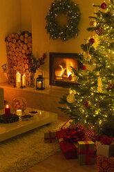 Ambient fireplace and candles illuminating living room with Christmas tree and decorations - HOXF01859
