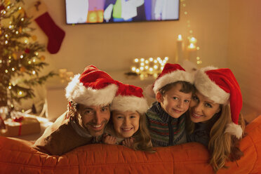 Porträt einer lächelnden Familie mit Weihnachtsmannmützen auf dem Wohnzimmersofa - HOXF01865