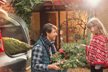 Vater und Tochter mit Weihnachtskranz vor dem Auto - HOXF01866