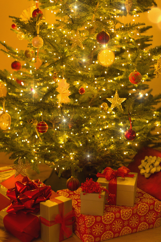 Beleuchteter Weihnachtsbaum mit Ornamenten und Geschenken, lizenzfreies Stockfoto