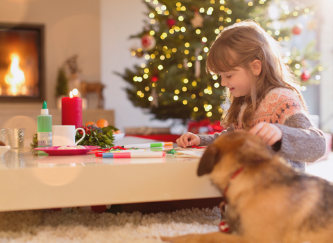 Hund beobachtet Mädchen Färbung mit Markern in Weihnachten Wohnzimmer, lizenzfreies Stockfoto