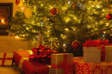 Gifts with red bows under illuminated Christmas tree - HOXF01889