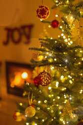 Weihnachtsschmuck am Weihnachtsbaum mit Lichterkette im Wohnzimmer - HOXF01895