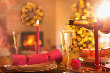 Einschenken von Champagner in eine Sektflöte auf dem Weihnachtstisch mit Weihnachtsgebäck - HOXF01927