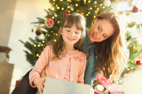 Mutter beobachtet Tochter beim Öffnen des Weihnachtsgeschenks - HOXF01930