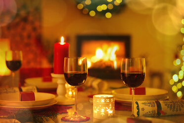 Rotwein und Kerzen auf dem stimmungsvollen Weihnachtstisch vor dem Kamin - HOXF01937