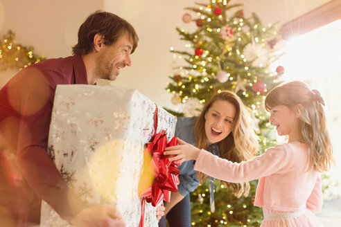 Eltern schenken ihrer Tochter ein großes Weihnachtsgeschenk unter dem Weihnachtsbaum - HOXF01939