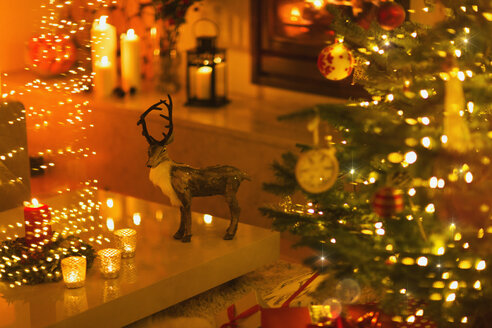 Rentierdekoration im stimmungsvollen Wohnzimmer mit Kerzen und Weihnachtsbaum - HOXF01940