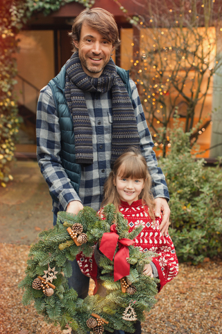 Portrait lächelnder Vater und Tochter mit Weihnachtskranz, lizenzfreies Stockfoto