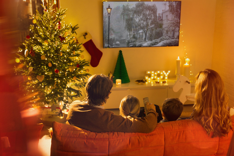 Familie beim Fernsehen im Weihnachtswohnzimmer, lizenzfreies Stockfoto