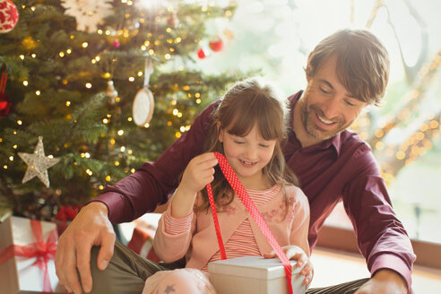 Vater beobachtet Tochter beim Öffnen des Weihnachtsgeschenks - HOXF01957