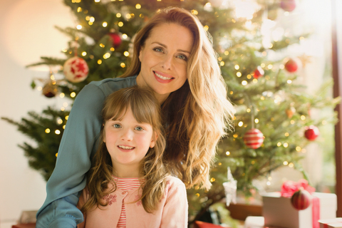 Porträt lächelnde Mutter und Tochter vor dem Weihnachtsbaum, lizenzfreies Stockfoto