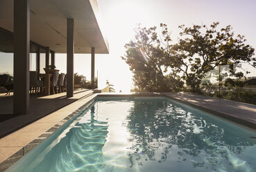 Reflection of tree in lap swimming pool outside modern luxury home showcase exterior - HOXF01987