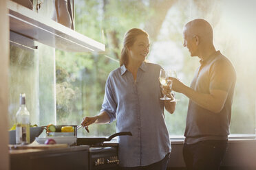 Couple toasting white wine glasses, cooking in kitchen - HOXF02007