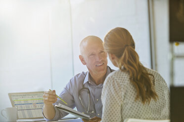 Male doctor discussing brochure with female patient in doctor’s office - HOXF02021