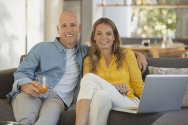 Portrait lächelndes reifes Paar mit Laptop auf dem Sofa - HOXF02069