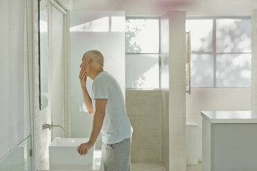Älterer Mann berührt Gesicht im Badezimmerspiegel - HOXF02074