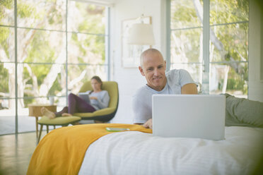 Älteres Paar entspannt sich, benutzt Laptop und Tablet im Schlafzimmer - HOXF02094