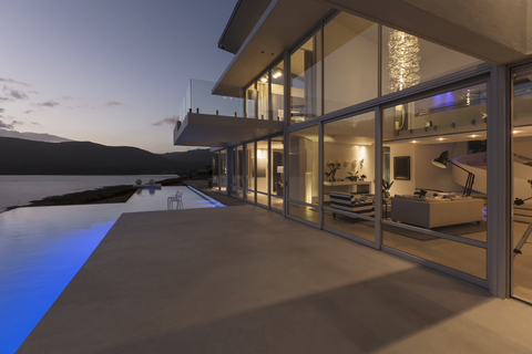 Ruhiges, modernes, luxuriöses Haus mit Außenbereich, Pool und Blick auf das Meer in der Abenddämmerung, lizenzfreies Stockfoto