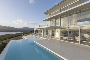 Sunny, tranquil modern luxury home showcase exterior with infinity pool - HOXF02102