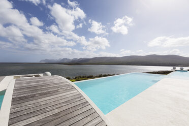 Sonniger moderner Luxus-Infinity-Pool mit Steg und Meerblick - HOXF02111