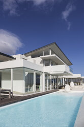 Sunny, tranquil modern luxury home showcase exterior with swimming pool under blue sky - HOXF02145