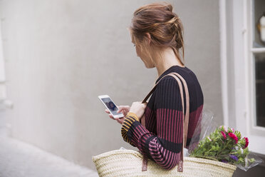 Woman video chatting with cell phone in alley - HOXF02217