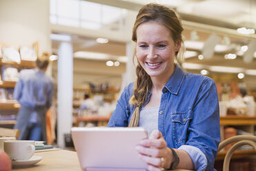 Smiling woman using digital tablet in cafe - HOXF02230