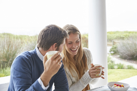 Lachendes Paar beim Kaffeetrinken auf der Veranda, lizenzfreies Stockfoto