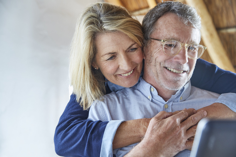 Affectionate couple hugging and using laptop stock photo