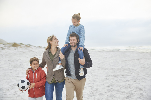 Familie mit Fußball am Winterstrand, lizenzfreies Stockfoto