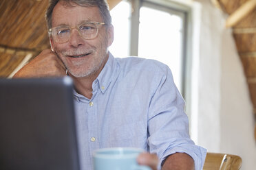 Senior man drinking coffee and using laptop - HOXF02247