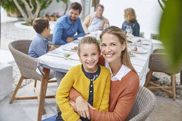 Porträt lächelnde Mutter und Tochter umarmen sich beim Mittagessen im Innenhof - HOXF02249