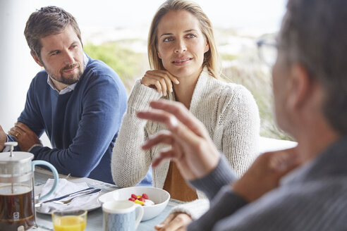 Familie genießt das Frühstück im Gespräch auf der Terrasse - HOXF02258