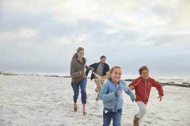 Playful family running on winter beach - HOXF02261