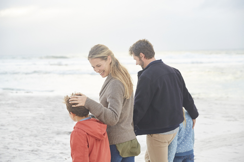 Lächelnde Familie beim Spaziergang am Winterstrand, lizenzfreies Stockfoto
