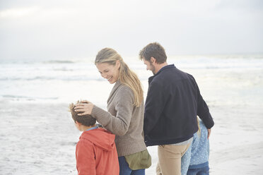 Smiling family walking on winter beach - HOXF02264