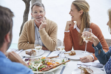 Couples drinking white wine and eating lunch at patio table - HOXF02266