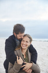 Smiling affectionate couple hugging on winter beach - HOXF02271