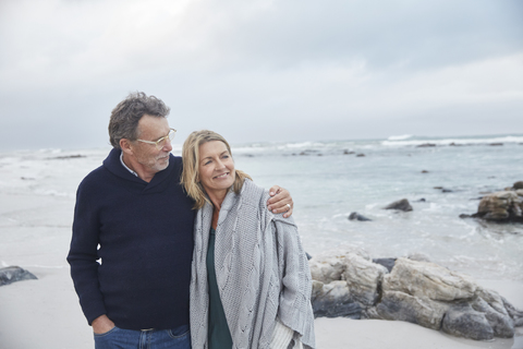 Affectionate couple hugging on winter beach stock photo