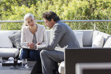 Geschäftsmann und Geschäftsfrau mit digitalem Tablet auf dem Sofa auf dem Balkon - HOXF02305