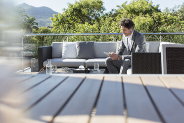 Geschäftsmann mit digitalen Tablet auf sonnigen Luxus Balkon Terrasse Sofa - HOXF02361